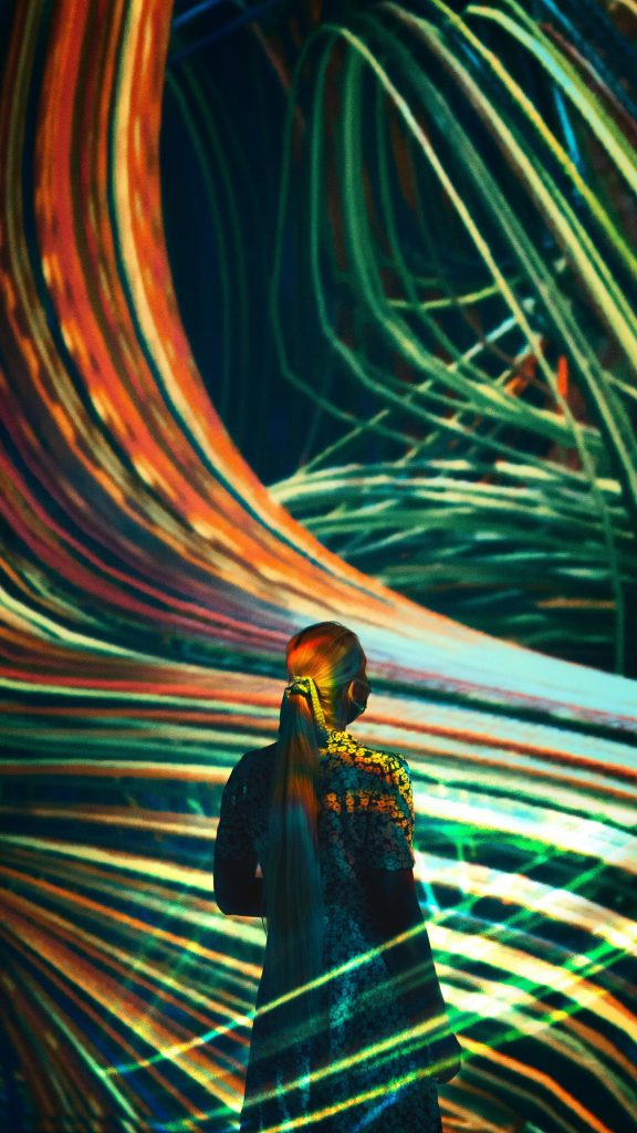 Femme de dos au milieu de bande de laser multicolores
